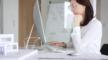 Ev planında çalışan ve masaüstü bilgisayarında tasarım yapan kadın mimar mimari bir proje geliştiriyor. İş ve mimari kavramı