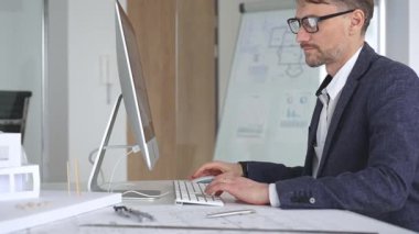 Profesyonel mimar, kaba yazılım ve fiziksel ölçekte bir model kullanarak yeni bir yapı projesi tasarlıyor. Planlarla dolu bir masada çalışıyorum. İş ve mimari kavramı