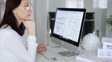 Ev planında çalışan ve masaüstü bilgisayarında tasarım yapan kadın mimar mimari bir proje geliştiriyor. İş ve mimari kavramı