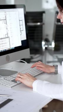 Profesyonel mimar kadın bilgisayar klavyesinde daktilo kullanıyor, planlara ve masadaki tasarım araçlarına nezaret ediyor, yeni mimari planlar yapıyor. İş ve mimari kavramı