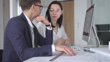 Profesyonel mimar takımı bilgisayar ekranında inşaat projesi planları ve mimari çizimleri tartışıyor. İş ve mimari kavramı