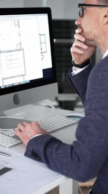 Modern ofiste klavyede yazan profesyonel mimar, planlar, ölçek modelleri ve tasarım araçları ile çevrili, planlama projesi. İş ve mimari kavramı