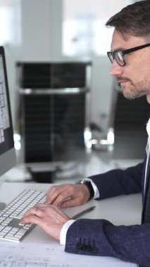 Planlar ve mimari model üzerinde çalışan mimar, ofisteki bilgisayar yazılımını kullanarak yeni bir bina projesi planlıyor. İş ve mimari kavramı