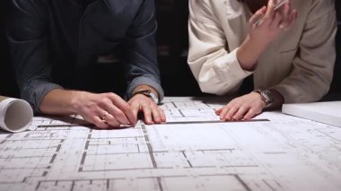 Mimarlık uzmanları teknik planları analiz ediyor ve yeni bir şehir gelişimi tasarlamak için taslak araçları kullanıyorlar. Yakınlardaki ölçekli bir modelle inşaat planlama ve mühendislik tasarımına odaklanıyor.