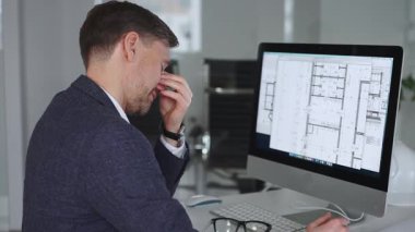 Stresli iş adamı ofis masasında baş ağrısı ve duygusal çöküntü yaşıyor, mimari projelerin teslim tarihleri ve iş baskısı altında eziliyor. İş ve mimari kavramı