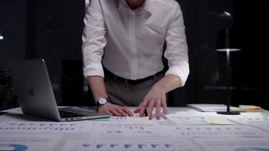 Profesyonel işadamı gece geç saatlere kadar ofiste çalışır, mali veri ve istatistikleri analiz eder, iş başarısı ve üretkenlik elde etmek için aşırı çalışma ve proje sürelerini yönetir