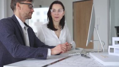 Profesyonel mimar takımı bilgisayar ekranında inşaat projesi planları ve mimari çizimleri tartışıyor. İş ve mimari kavramı