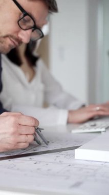 Bina planlarını tartışan profesyoneller, yeni bir gelişme için ayrıntılı mimari çizimleri gözden geçirmek için pusula ve cetvel kullanıyorlar. İş adamları ve mimari konsepti