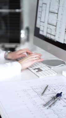 Bir bina projesi planlayan mimar veya mühendis, bir masaüstü bilgisayarındaki planları ve teknik çizimleri gözden geçiriyor. İş ve mimari kavramı