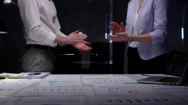 Karanlık bir ofiste el çırpan iş adamları, veri tabloları, finansal grafikler ve çalışan dizüstü bilgisayarlarla çevrili bir gece geç saatlerde yapılan toplantıda elde edilen başarıları kabul ediyorlar.