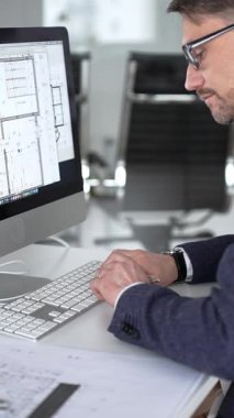 Modern ofiste klavyede yazan profesyonel mimar, planlar, ölçek modelleri ve tasarım araçları ile çevrili, planlama projesi. İş ve mimari kavramı