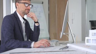 Bina tasarımı ve planlama üzerine odaklanan profesyonel mimar, bir bilgisayar ve fiziksel modelin planlarıyla çalışıyor. İş ve mimari kavramı