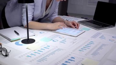 Finans raporlarını, çizelgeleri ve hesap tablolarını beyaz bir masada inceleyen, not alan bir iş adamı, bütçe, planlama ve analitik kararlar için bir bar grafiği gösterirken,