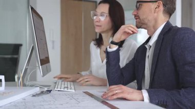 Profesyonel mimar takımı bilgisayar ekranında inşaat projesi planları ve mimari çizimleri tartışıyor. İş ve mimari kavramı