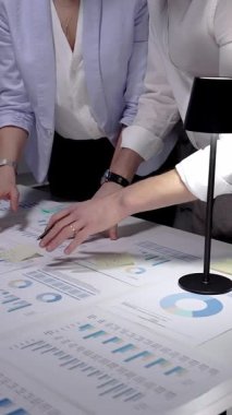 Bir şirket toplantısına katılan iş adamları, birlikte finansal belgeleri, piyasa araştırma raporlarını ve masa üzerinde sergilenen iş analizlerini analiz ediyorlar.