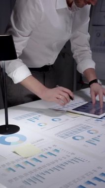 Finansal verileri ve piyasa istatistiklerini analiz eden, büyüme eğilimlerini hesaplayan, stratejik kararlar veren ve bir ofis masasında birçok tabloda gelecek yatırımları planlayan iş adamları.