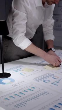 Finansal verileri ve piyasa istatistiklerini analiz eden, büyüme eğilimlerini hesaplayan, stratejik kararlar veren ve bir ofis masasında birçok tabloda gelecek yatırımları planlayan iş adamları.