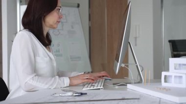 Profesyonel kadın, ofis çalışma alanındaki masasında teknoloji ve fiziksel modeller kullanarak mimari tasarımlar yaratmaya odaklandı. İş ve mimari kavramı