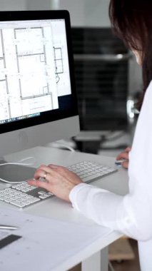 Profesyonel mimar kadın bilgisayar klavyesinde daktilo kullanıyor, planlara ve masadaki tasarım araçlarına nezaret ediyor, yeni mimari planlar yapıyor. İş ve mimari kavramı