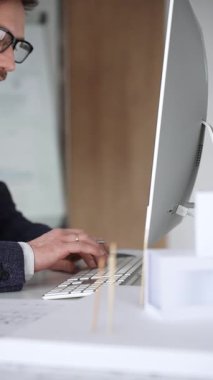 Erkek mimar, mimari bir stüdyoda yeni yapılar ve modeller tasarlayarak bilgisayar ekranına ve planlara derinden odaklanmıştır. İş ve mimari kavramı