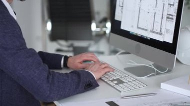 Bilgisayarda çalışan bir mimar, klavyede yazı yazan eller, yeni inşaat için kat planları ve mühendislik planları geliştiren bir mimar. İş ve mimari kavramı