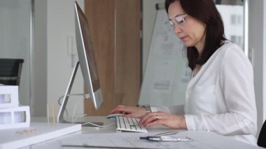 Bilgisayarda çalışan kadın mimar, yeni mimari projeler tasarlıyor, inşaat ve emlak gelişimini düşünüyor. İş ve mimari kavramı