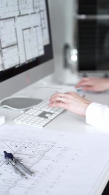 Bir bina projesi planlayan mimar veya mühendis, bir masaüstü bilgisayarındaki planları ve teknik çizimleri gözden geçiriyor. İş ve mimari kavramı