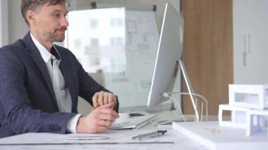 Profesyonel mimar, kaba yazılım ve fiziksel ölçekte bir model kullanarak yeni bir yapı projesi tasarlıyor. Planlarla dolu bir masada çalışıyorum. İş ve mimari kavramı