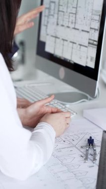 Dijital ve fiziksel yapı planlarını inceleyerek, mimari tasarım projesinde işbirliği yapan mühendislik uzmanları. İş adamları ve mimari konsepti