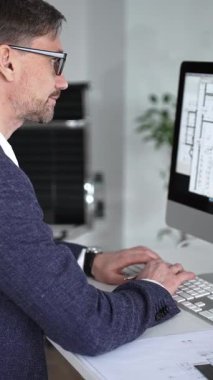 Modern ofiste klavyede yazan profesyonel mimar, planlar, ölçek modelleri ve tasarım araçları ile çevrili, planlama projesi. İş ve mimari kavramı