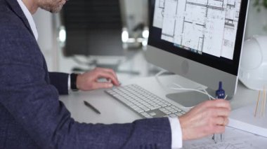 Bilgisayarda çalışan bir mimar, klavyede yazı yazan eller, yeni inşaat için kat planları ve mühendislik planları geliştiren bir mimar. İş ve mimari kavramı