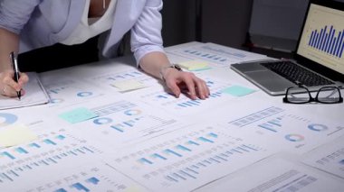 Finansal tablolar ve iş raporlarını incelemek için tablet kullanan profesyonel bir iş kadını strateji ve planlama için veri belgeleriyle dolu bir ofis masasında geç saatlere kadar çalışıyor.