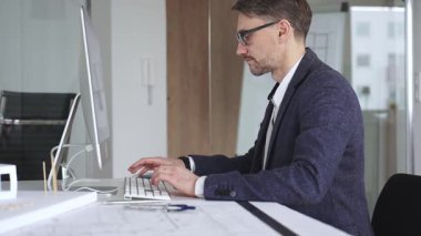 Erkek mimar, mimari bir stüdyoda yeni yapılar ve modeller tasarlayarak bilgisayar ekranına ve planlara derinden odaklanmıştır. İş ve mimari kavramı