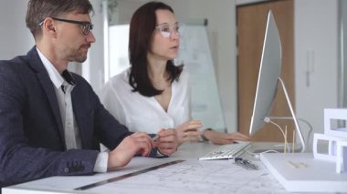 Profesyonel mimar takımı bilgisayar ekranında inşaat projesi planları ve mimari çizimleri tartışıyor. İş ve mimari kavramı