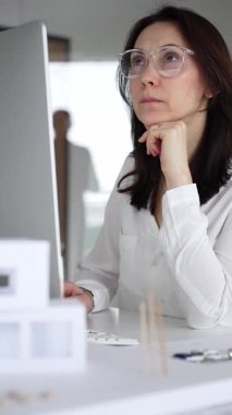 Mimari proje planlayan kadın, planlar ve bilgisayar üzerinde çalışıyor. Modern mimarlık bürosu