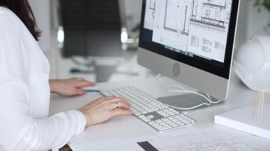 Kadın mimarların elleri klavyede yazı yazıyor, fareyi manipüle ediyor, mühendislik ve kentsel planlama için dijital planlar üzerinde çalışıyor. İş ve mimari kavramı