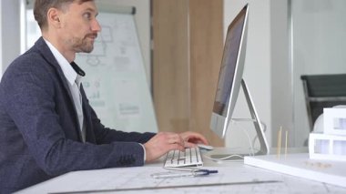 Erkek mimar ekranda dijital planları ve mimari çizimleri inceleyerek tasarım ve inşaat projesi yaratıyor. İş ve mimari kavramı