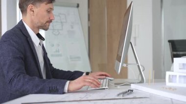 Erkek mimar ekranda dijital planları ve mimari çizimleri inceleyerek tasarım ve inşaat projesi yaratıyor. İş ve mimari kavramı