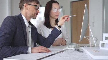 Profesyonel mimar takımı bilgisayar ekranında inşaat projesi planları ve mimari çizimleri tartışıyor. İş ve mimari kavramı