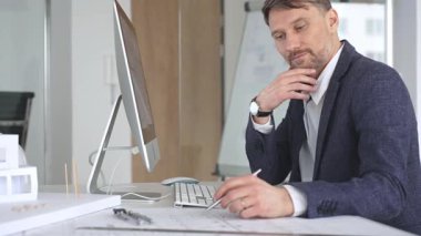 Bina tasarımı ve planlama üzerine odaklanan profesyonel mimar, bir bilgisayar ve fiziksel modelin planlarıyla çalışıyor. İş ve mimari kavramı