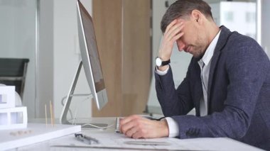 Stresli iş adamı ofis masasında baş ağrısı ve duygusal çöküntü yaşıyor, mimari projelerin teslim tarihleri ve iş baskısı altında eziliyor. İş ve mimari kavramı