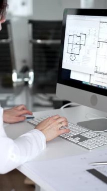 Profesyonel mimar kadın bilgisayar klavyesinde daktilo kullanıyor, planlara ve masadaki tasarım araçlarına nezaret ediyor, yeni mimari planlar yapıyor. İş ve mimari kavramı