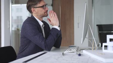 Profesyonel mimar, bir masada oturmuş proje geliştirmeyi düşünürken planlar ve tasarım planlarını analiz ediyor. İş ve mimari kavramı