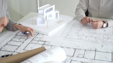 Modern mimari projesinde işbirliği yapan mimarlar, bina tasarımı, planlama, yaratıcılık ve sürdürülebilir inşaatın vurgulanması için ayrıntılı planlar ve 3D modeli gözden geçiriyorlar.