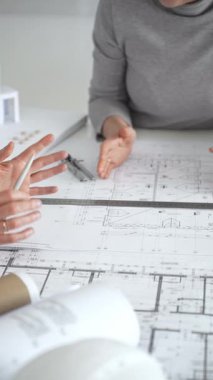 Mimarlar planları ve mimari modelleri inceliyor, profesyonel bir ofis toplantısında tasarım ve şehir planlamasını tartışıyor, gelecekteki inşaat projeleri üzerinde işbirliği yapıyor, kapatıyorlar.