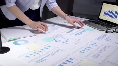 İş kadını kurumsal mali verileri analiz ediyor, istatistik ve pazar eğilimlerini yönetiyor, belgeleri inceliyor, yatırım stratejisi planlıyor, ofiste yıllık bir rapor üzerinde çalışıyor
