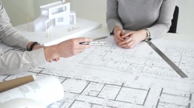 Mimarlar proje planları üzerinde işbirliği yapıyor, mimari tasarımları tartışıyor, inşaat planları geliştiriyor, ofis masasında kavramsal bir model ev yaratıyor, kapatıyorlar.