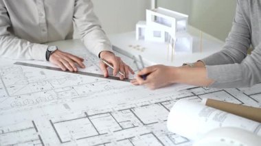 Modern mimari projesinde işbirliği yapan mimarlar, bina tasarımı, planlama, yaratıcılık ve sürdürülebilir inşaatın vurgulanması için ayrıntılı planlar ve 3D modeli gözden geçiriyorlar.