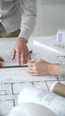 Mimarlar yeni bina tasarımını tartışıyor, ayrıntılı planların üzerinde bir pusula tutuyor, modern bir ofis düzeninde ev mimarisi modeliyle proje geliştirmede işbirliği yapıyor,