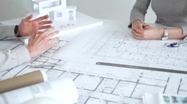 Mimarlar küçük bir ev modelinin ayrıntılı planlarını çizer ve ölçerler, bir konut tasarımı projesi için kesin takım çalışması, planlama ve işbirliği vurgulanır, kapat